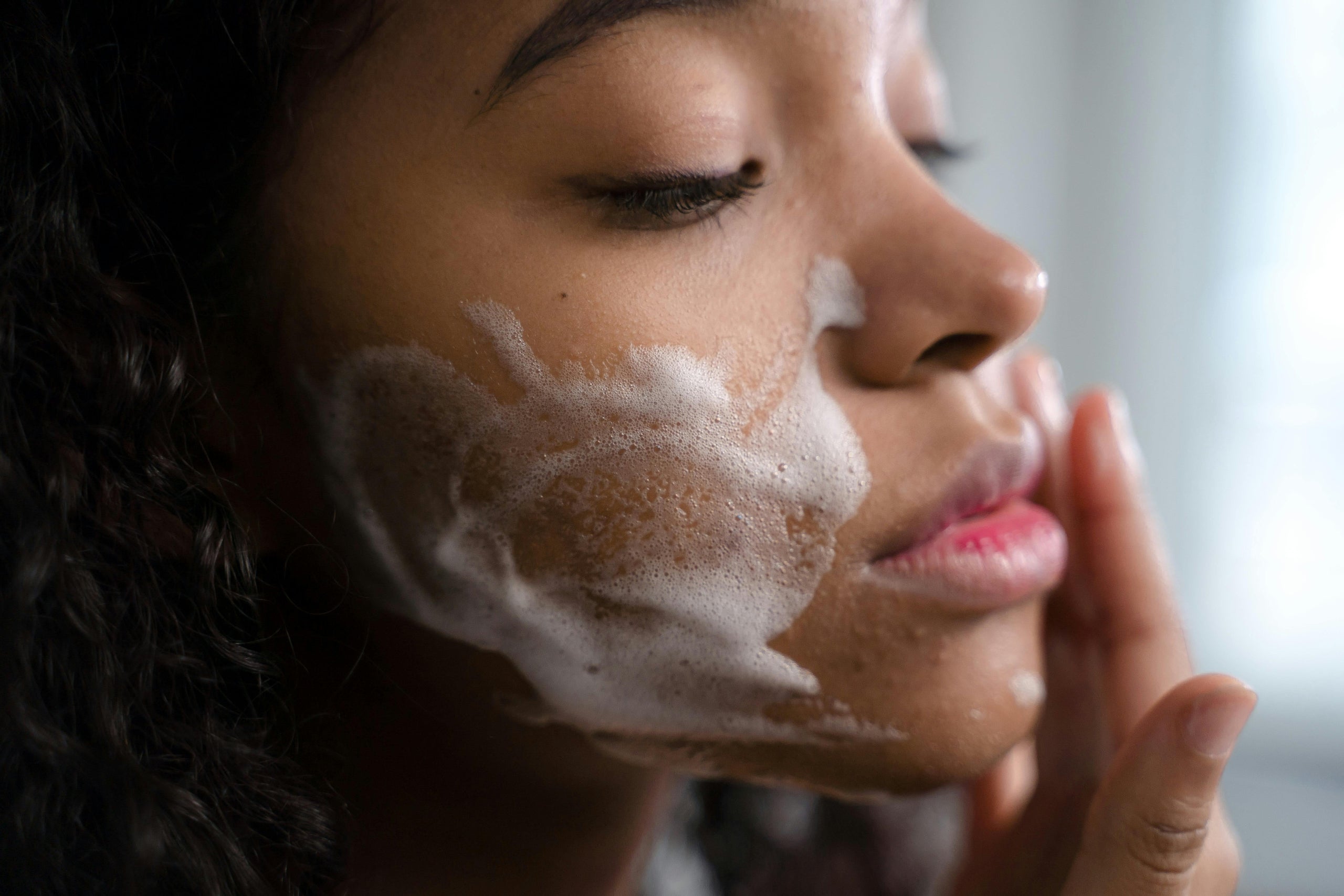 Woman applying facial soap to her face with a blurred backgroundslider_item_gDcghX